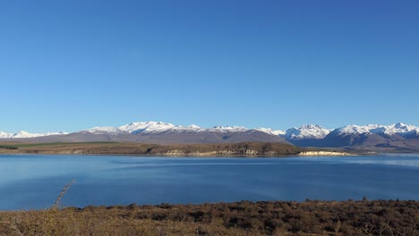 hora dorada, pan de pleno invierno a través de un hermoso lago alpino azul tinta con majestuosas montañas en la distancia