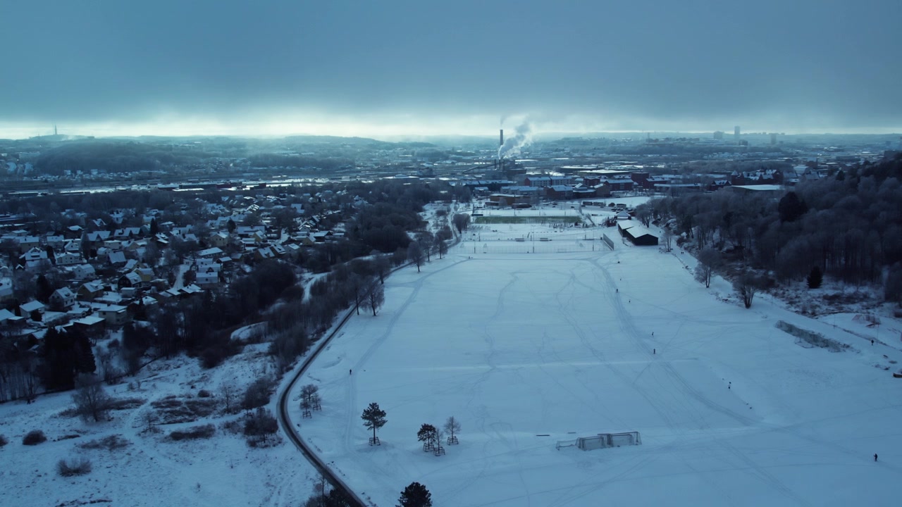 Aerial drone view of snow covered Kviberg Park in Gothenburg Sweden featuring open parkland winter landscape surrounding neighborhoods and distant city skyline