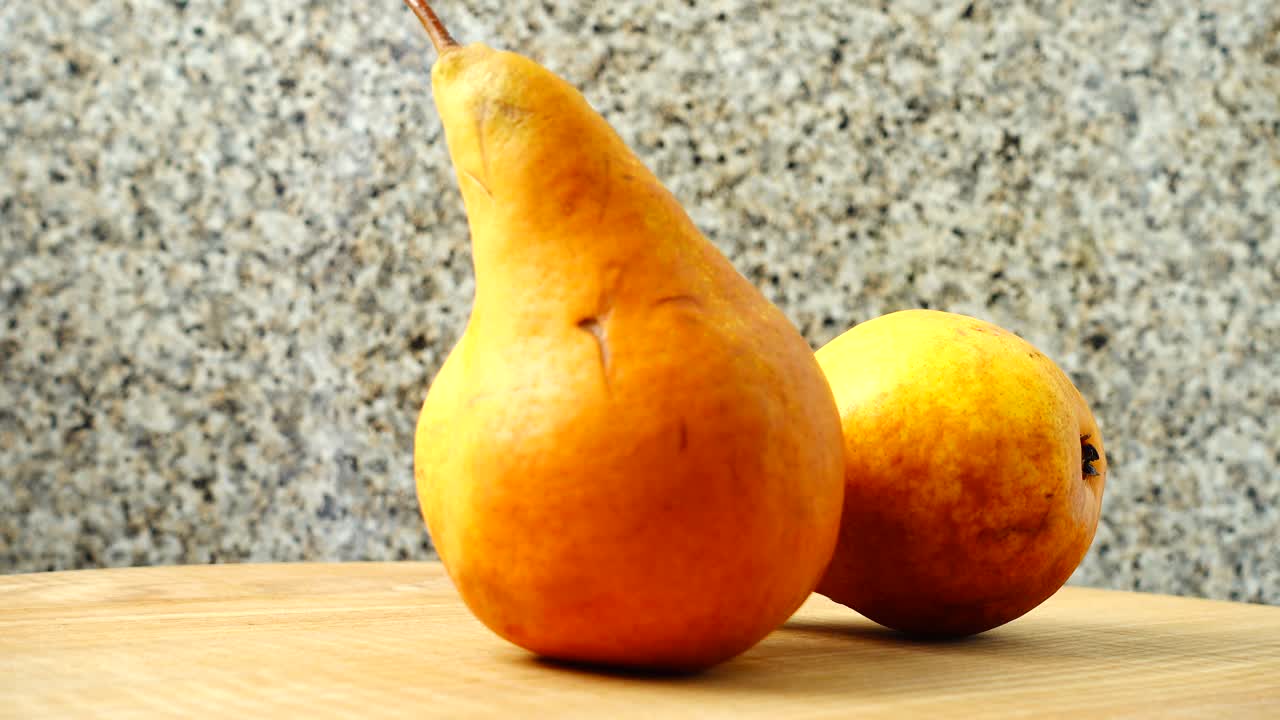 Pere su un tagliere di legno in cucina. Ripresa in movimento