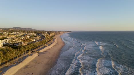 scenic aerial view of pacific ocean waves breaking into california shoreline