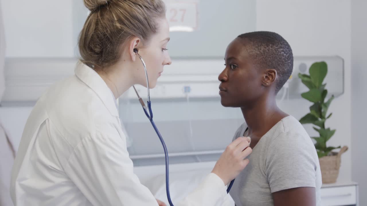 paciente femenina diversa y médico usando un estetoscopio en su pecho en el hospital, en cámara lenta
