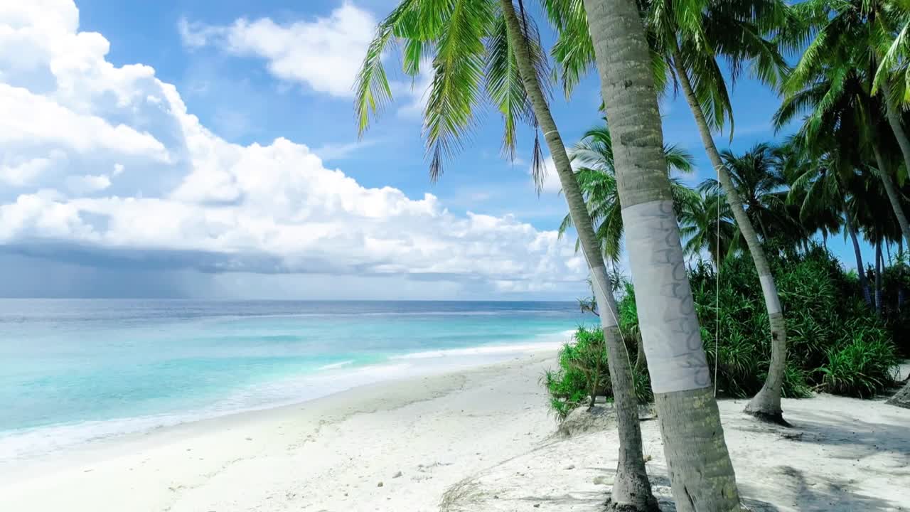 Beautiful tropical beach with soft white sand, lush palm trees, turquoise sea and blue sky with clouds creating a relaxing paradise scene perfect for travel and holiday destinations