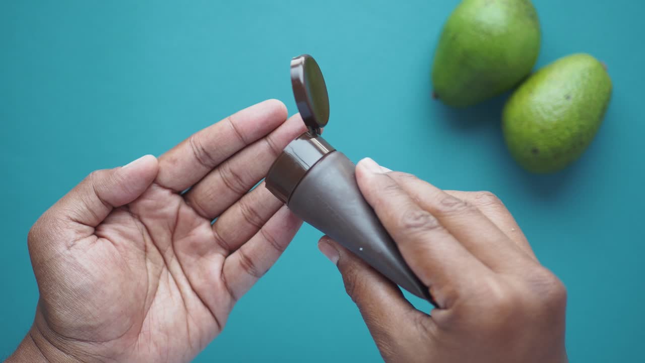 persona que aplica crema de aguacate en su mano