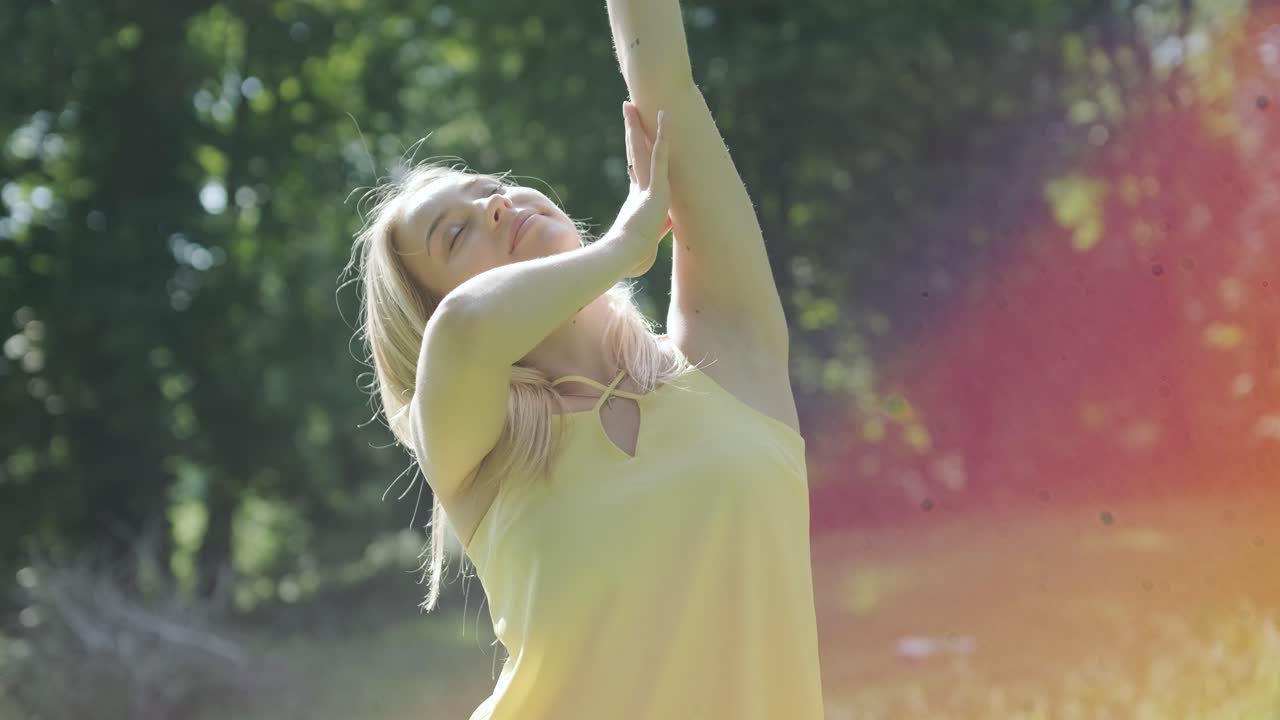 Giovane ragazza felice e bella che balla in libertà in un parco estivo con alberi sullo sfondo