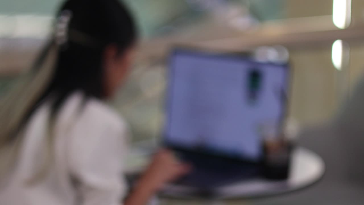 mujer enfocada usando una computadora portátil en un café de bangkok