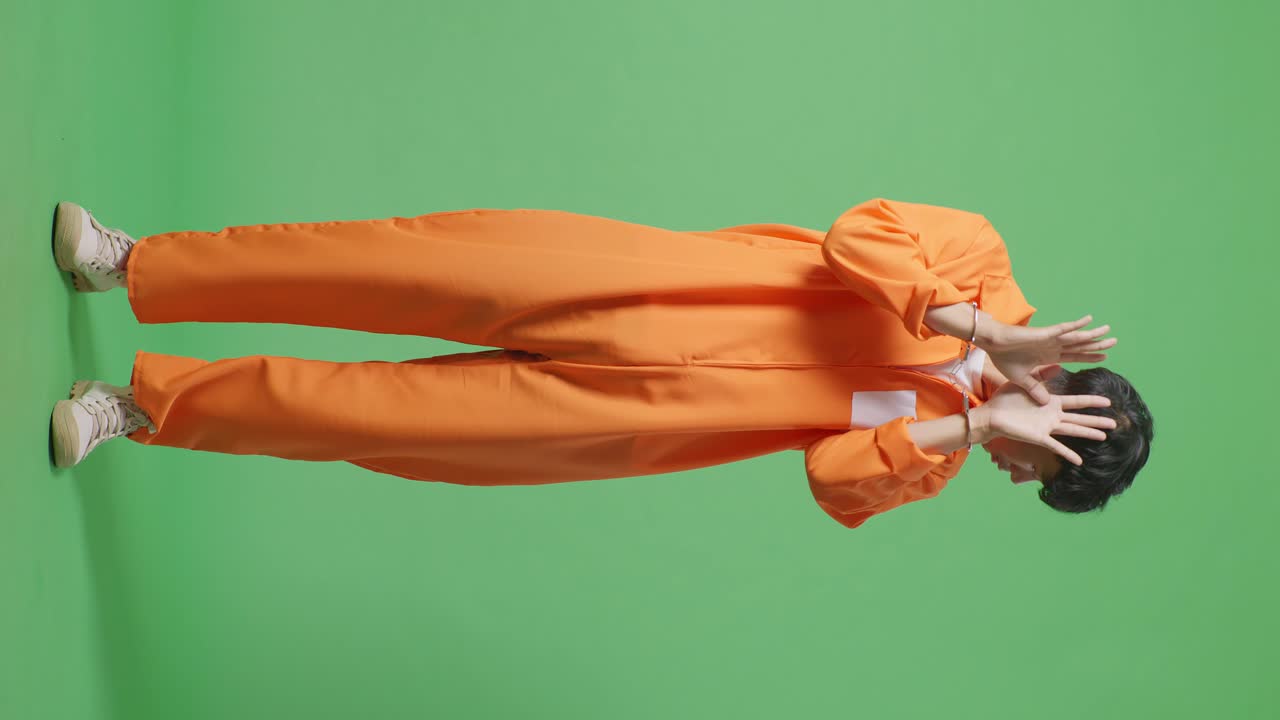 손을 은 아시아 남성 수감자의 몸이 녹색 스크린 배경에 서서 손바닥 표정을 보여 카메라에 의해 포착되기를 원하지 않는 표정을 보여줍니다.