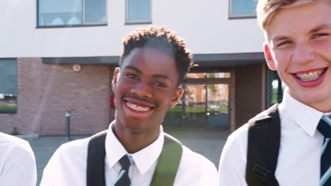 portrait of smiling male high school students wearing uniform outside college building