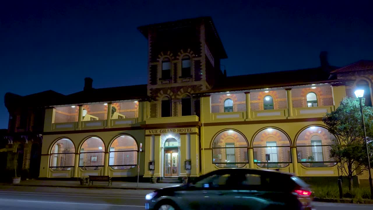 A car passes the illuminated Vue Grand Hotel at night in Queenscliff, Victoria, showcasing its architectural elegance