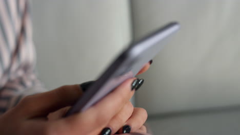 Teenager-hand-using-mobile-phone-at-home-closeup.-Girl-surfing-social-media