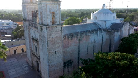 aerial closeup boom up with sun behind of the cathedral de san gervasio just after sunrise in valladolid, yucatan, mexico