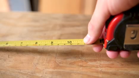 Slow-motion-pulling-a-tape-measure-across-a-piece-of-plywood-and-having-it-run-through-someone's-hands