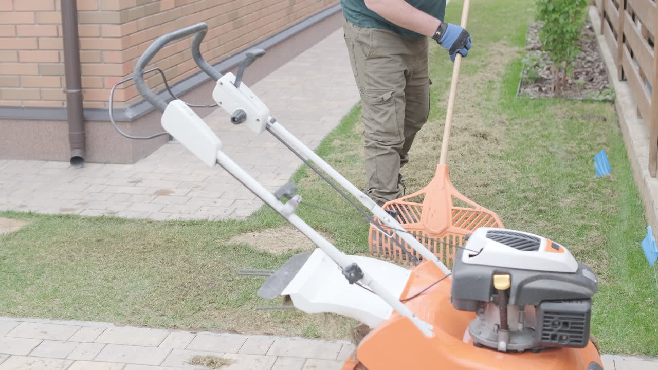 Man Raking Dry Grass in a Residential Garden