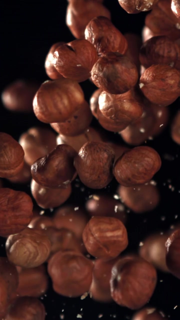 Nocciole pelate che cadono al rallentatore su sfondo nero
