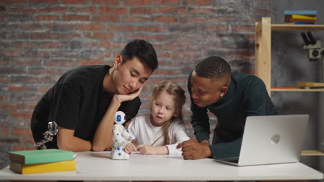 Little-girl-with-science-teachers-look-at-toy-robot-on-table