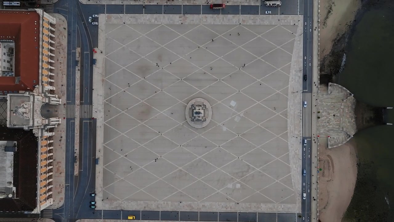 Top-down drone shot of Commerce square and Rua Augusta Arch, Lisbon at sunrise. Few people in square. Portugal