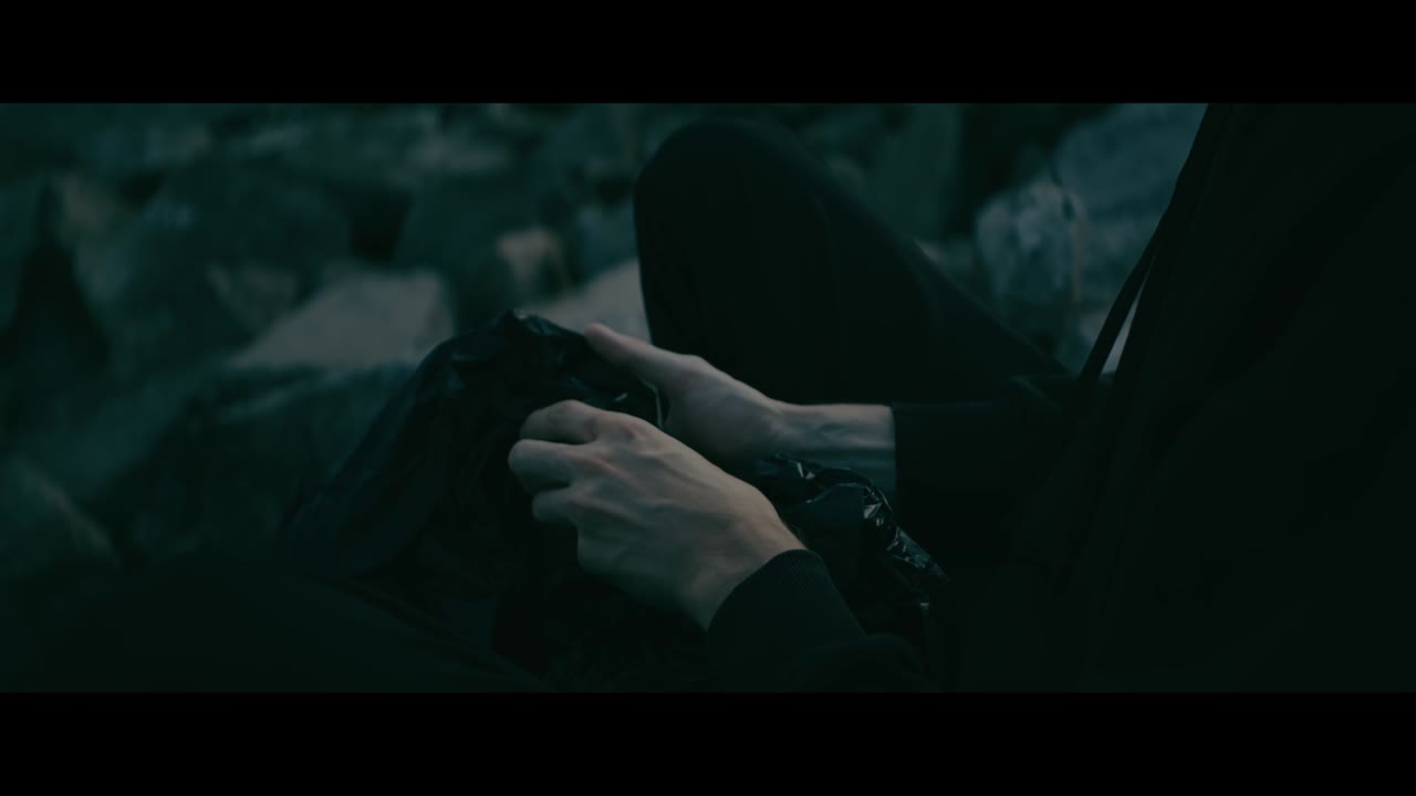 Person sitting outdoors handling garbage