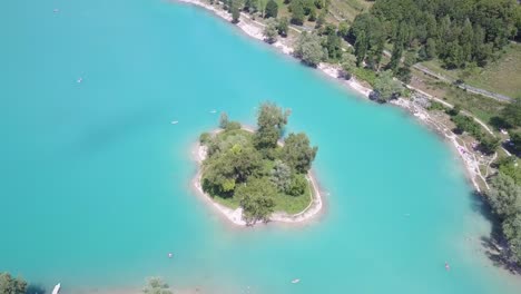 drone disparó la rotación de una pequeña isla verde en medio del hermoso lago azul di tenno en la dolomita, italia