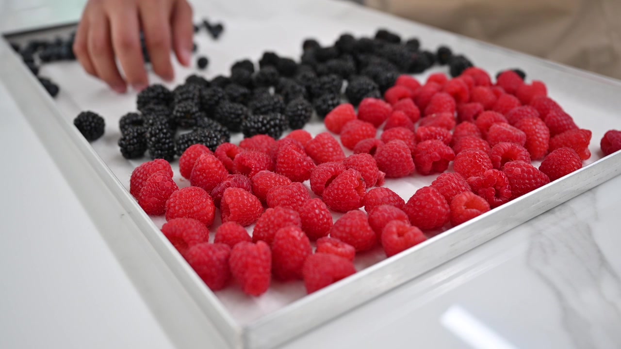A baker organized fresh berries showcased for cake and muffin toppings at a local bakery.