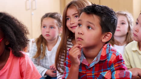 elementary school pupils listen and smile in class, close up