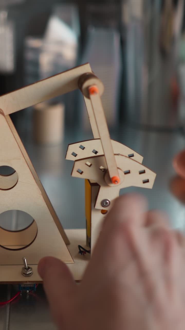 pov de manos montando un modelo de bomba de aceite de madera en un escritorio, mostrando la ingeniería y el diseño en progreso