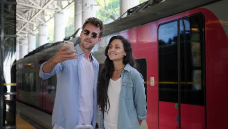 una pareja tomando una selfie en la estación de tren.