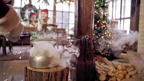 close up of steaming teapot. santa claus's hand is taking the kettle. new year and christmas concept. feast is coming. specialy decorated room.