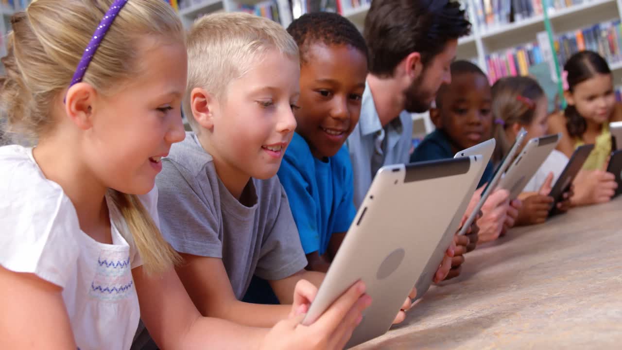 School kids and teacher using digital tablet in library