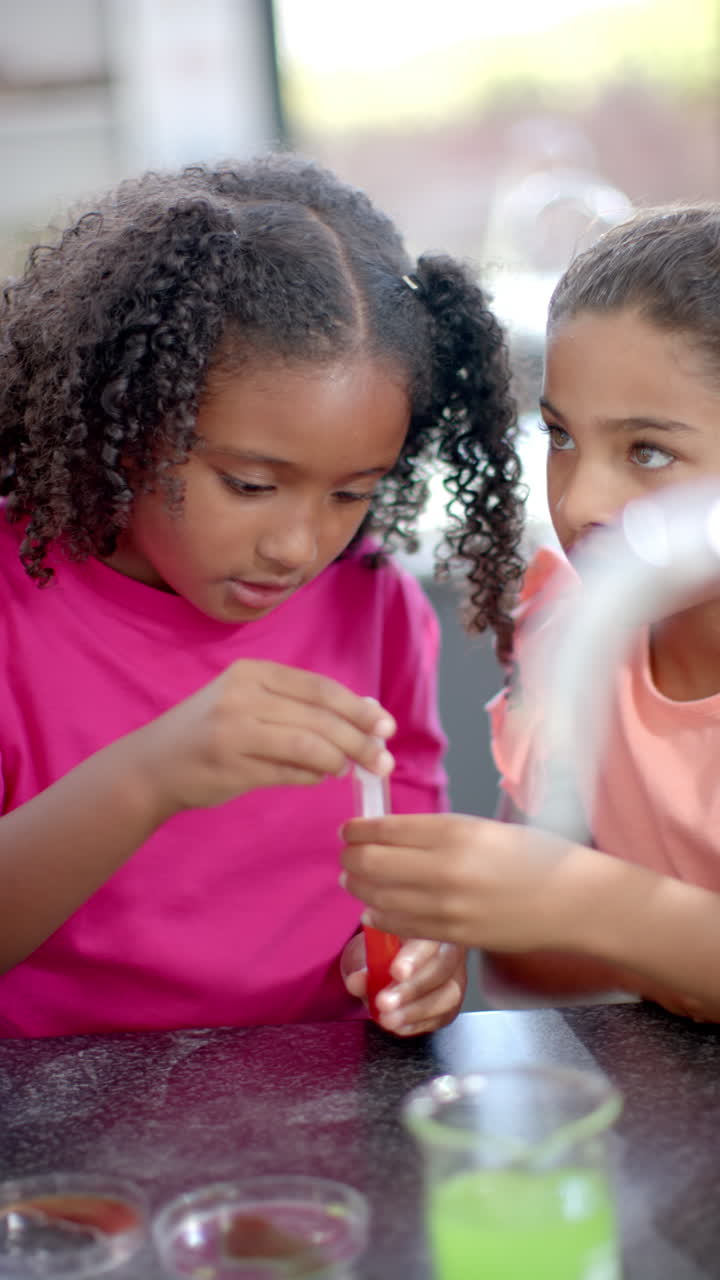Vertical video: In school, two young girls are focusing on science experiment