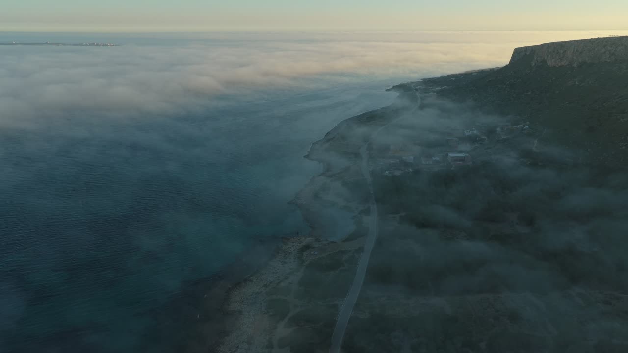 Foggy coastal road aerial view revealing the santa pola lighthouse