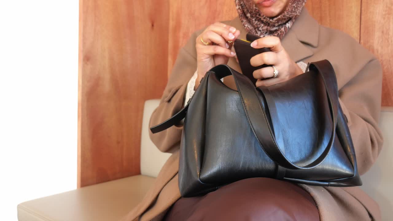 Donna che tira fuori il portafoglio dalla sua borsa nera