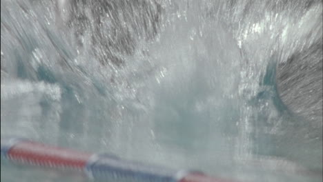 a woman leans over and dives into the pool and begins to swim