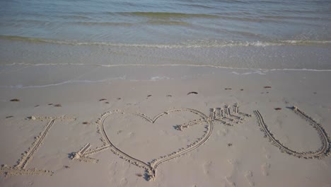 static shot of i love you inscribed in the sand on a beach