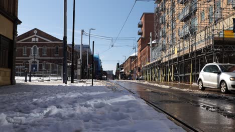 Conducción-De-Automóviles-En-Una-Calle-De-La-Ciudad-Soleada-Y-Nevada-Cerca-De-Las-Líneas-De-Tranvía,-Sheffield,-ángulo-Bajo