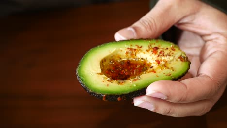 hand holding a seasoned avocado half