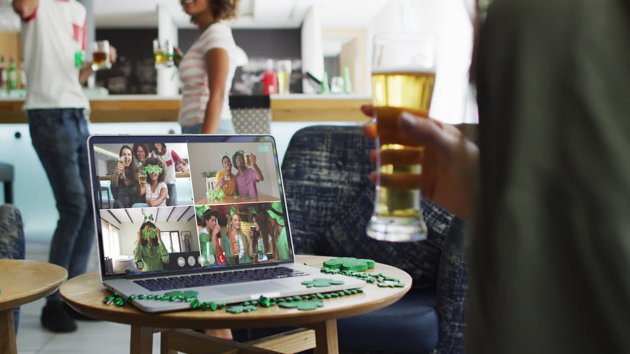 Person at bar using laptop making st patrick's day video call with friends at another bar