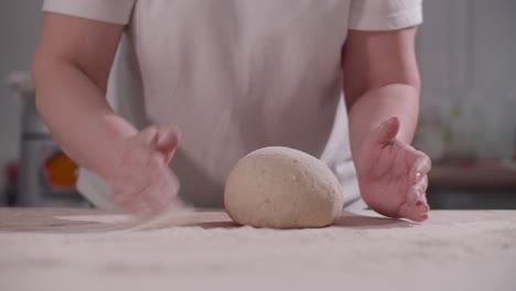 female hands knead and toss dough on kitchen