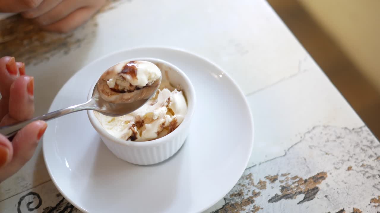 초콜릿 소스와 함께 바닐라 아이스크림을 먹는 여자