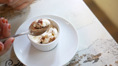 mujer comiendo una cuchara de helado de vainilla con salsa de chocolate