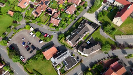 cars on street of neighborhood during sunny day. solar panels on roof of homes. aerial top down flyover. sunny day in summer with green trees.