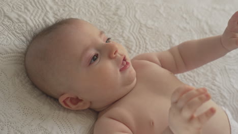 Mommy-taking-care-washing-baby's-face-eyes-with-cotton-pad,-in-white-bedroom