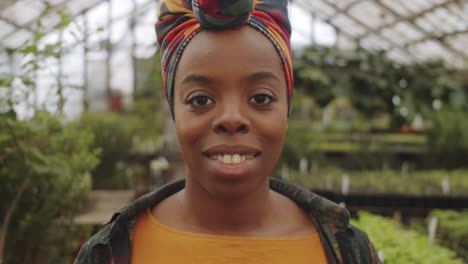 portrait of cheerful african american female farmer in greenhouse