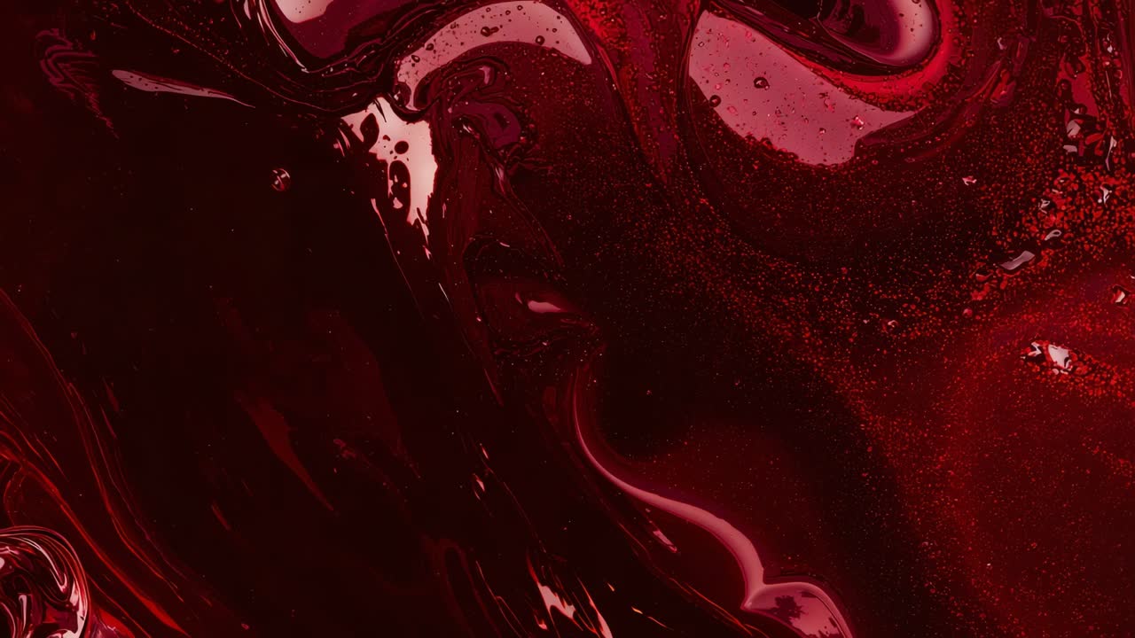 Shifting burgundy liquid surface reacting to light in studio close-up showing ripples and bubbles