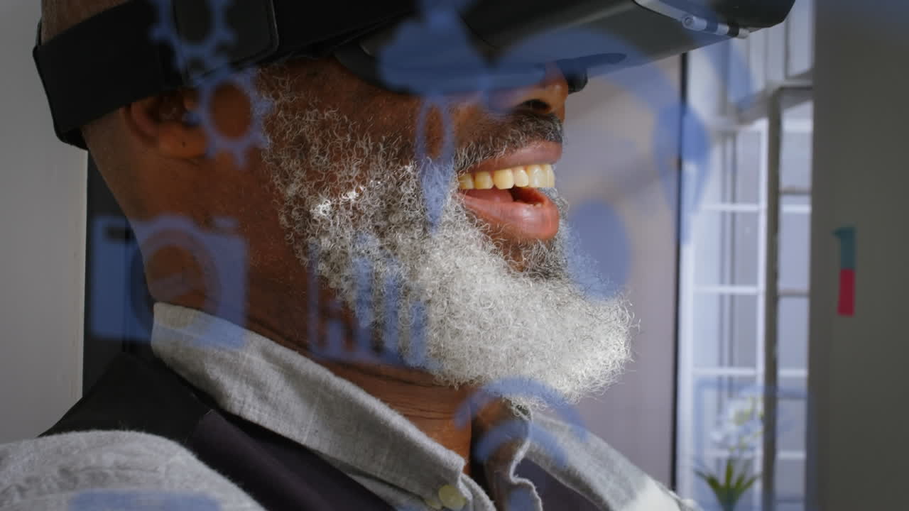 Flera blå digitala ikoner mot en afroamerikansk äldre affärsman med VR-headset på kontoret.