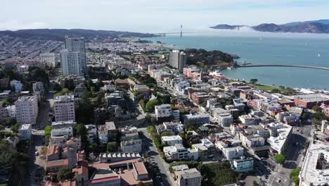 un largo dron disparó en san francisco sobrevolando el área de fisherman&#39;s wharf hacia la plaza marítima y la plaza ghirardelli con el puente golden gate al fondo