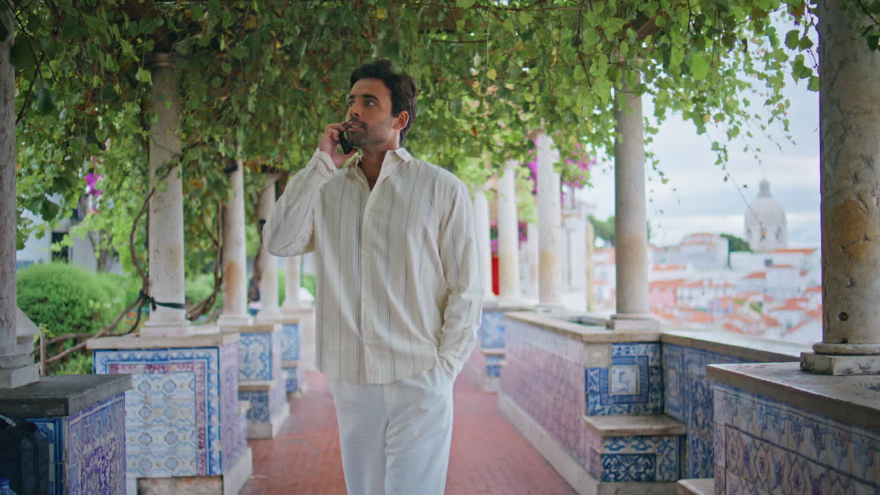 un caballero descansando llamando por teléfono celular paseando por el jardín de la ciudad. un hombre hablando por teléfono móvil