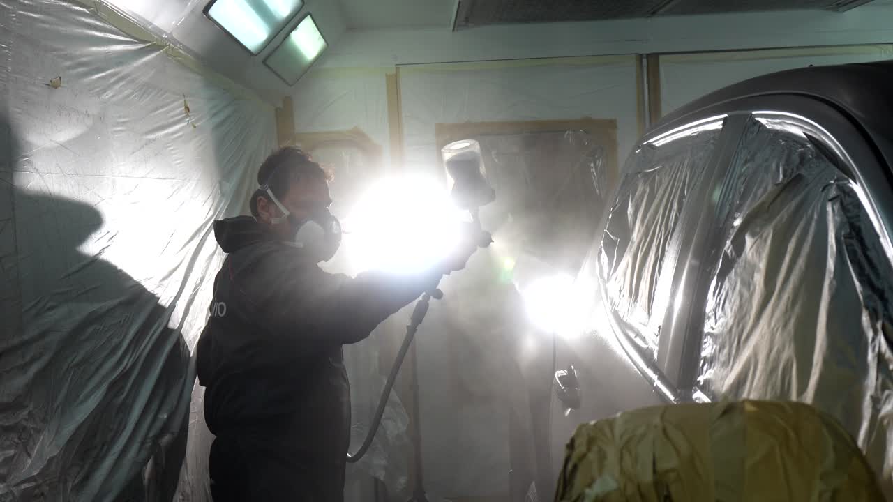 Man Spray Painting Car in a Professional Auto Repair Workshop