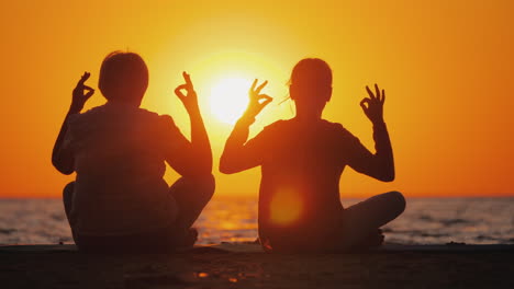 grandmother and granddaughter meditate on the beach active and healthy seniors concept