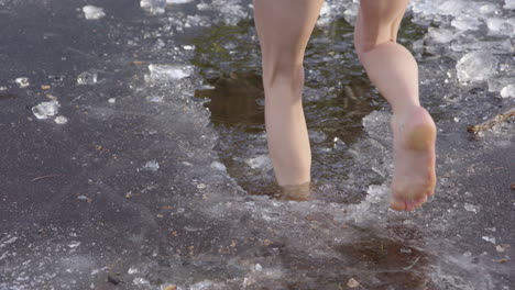 beautiful legs of a young woman walking into icy water, jumps out