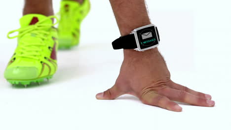 atleta en posición inicial con un reloj inteligente alrededor de su cintura