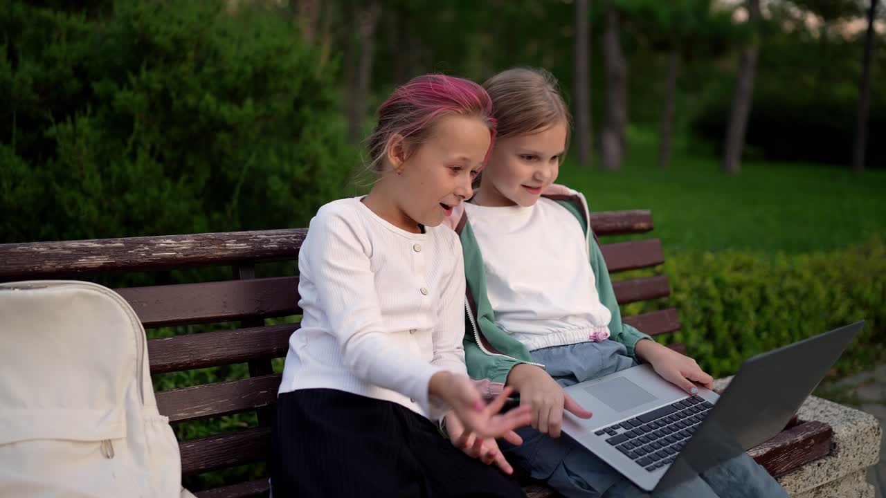 dos chicas usando una computadora portátil en el parque